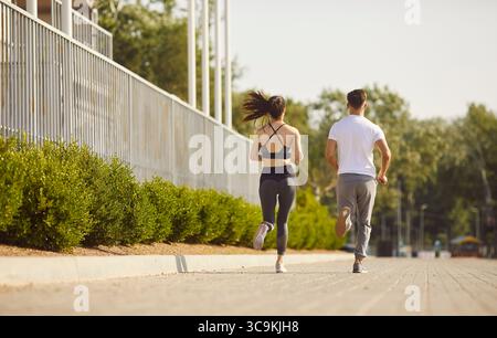 Vista posteriore di coppie sportive che indossano abbigliamento sportivo e che fanno jogging insieme nel parco. Foto Stock