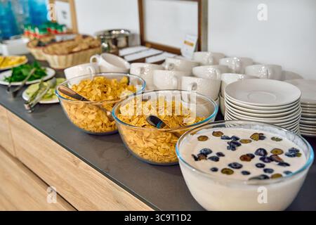 Un vivace buffet per la colazione con cereali croccanti, frutta fresca e cremoso yogurt circondato da eleganti stoviglie Foto Stock