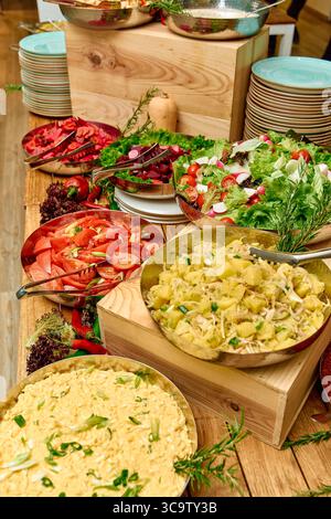 Una colorata gamma di contorni preparati al momento, tra cui insalate, pasta e verdure esposte su un tavolo rustico per un'esperienza culinaria vivace Foto Stock