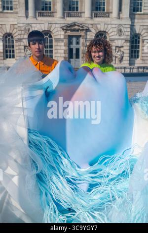 Londra, Regno Unito. 6 agosto 2025. Staff con "The Spell or the Dream" dell'artista vincitore del Turner, Tai Shani, alla Somerset House. La commissione celebra il 25° compleanno di Somerset House e comprende una figura scultorea luminosa, simile a quella della bella addormentata, che si trova all'interno di una vitrina simile a un vetro, una stazione radio digitale del 24/7, cabine di ascolto, accompagnata da un programma di eventi dal vivo. Crediti: Stephen Chung / Alamy Live News Foto Stock