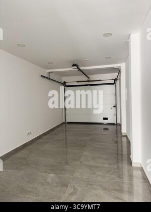 Garage pulito e spazioso con porta motorizzata e interni dal design elegante. Foto Stock