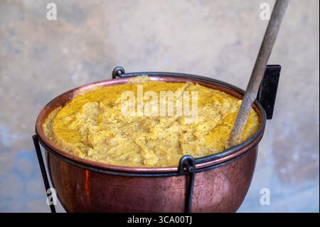 Primo piano di una pentola di rame che cucina la polenta, un piatto tradizionale italiano Foto Stock