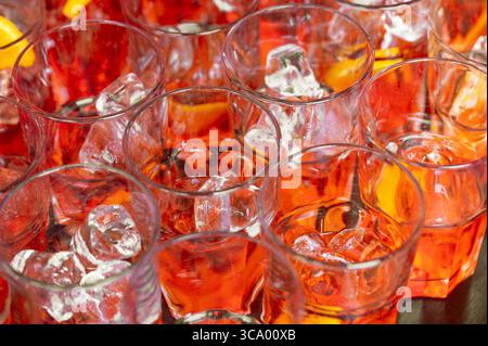 Molti bicchieri riempiti con un rinfrescante cocktail Aperol spritz e cubetti di ghiaccio, pronti per essere serviti a una festa Foto Stock