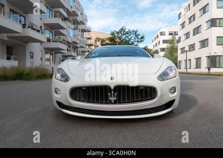 Maserati bianca vista frontale auto sportiva con logo mascherina anteriore tridente Maserati. Grandangolo con angolo basso, scatto. Parcheggiato da un moderno appartamento e ufficio Foto Stock