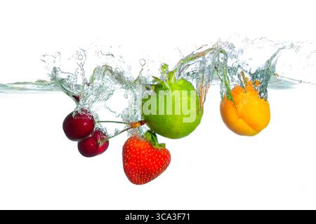 Vivace assortimento di frutta fresca, tra cui ciliegie, fragole, lime e albicocche che spruzzano in acqua limpida, creando increspature e schizzi dinamici Foto Stock