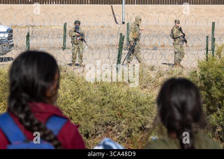I bambini guardano mentre i soldati pattugliano il confine con il filo spinato vicino a Ciudad Juarez, un punto di riferimento per i problemi migratori. Foto Stock