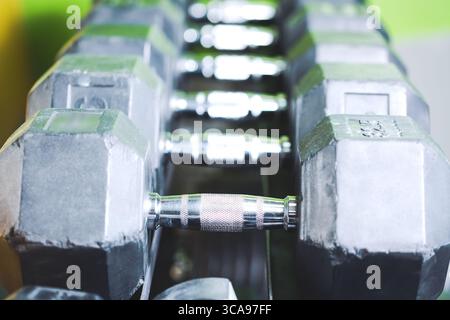 Concetto di sport fitness. Set di manubri neri. Avvicinati a molti manubri in metallo sul rack nel centro fitness sportivo. Messa a fuoco selettiva Foto Stock