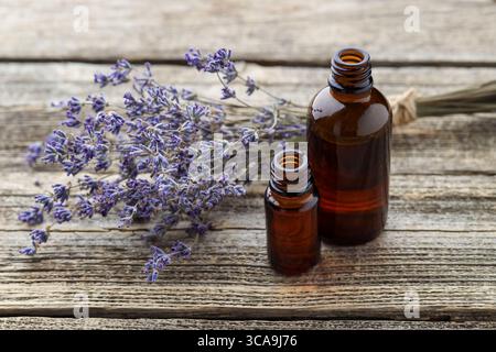 Olio essenziale di lavanda in bottiglie con fiori su tavola di legno Foto Stock