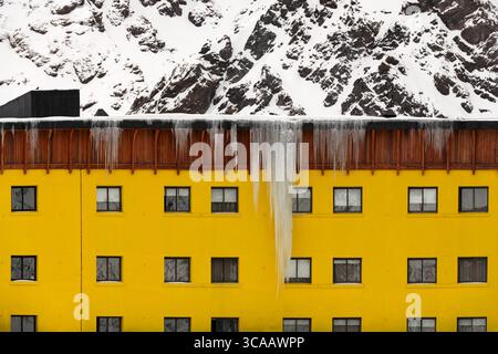 Portillo, Cile: Un primo piano della facciata dell'Hotel Portillo in Cile, con una suggestiva parete gialla che contrasta con la montagna innevata. Foto Stock