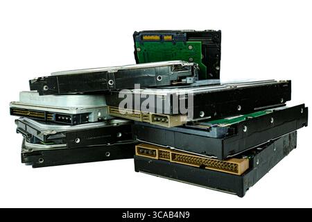 Stack di vecchi dischi rigidi di grandi dimensioni con connettori vintage e circuiti stampati verdi esposti, disposti su sfondo bianco, a simboleggiare la tecnologia obsoleta. Foto Stock