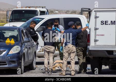 Gli agenti indagano su una scena del crimine attorno a un veicolo danneggiato a Ciudad Juarez, una città afflitta da violenza urbana. Foto Stock