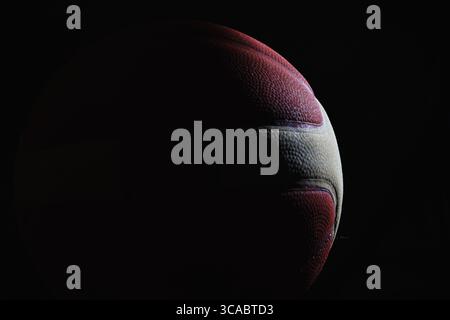 Primo piano di una pallacanestro rossa con strisce bianche su sfondo nero Foto Stock