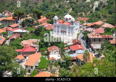Vista aerea che cattura il villaggio di Pedoulas con tetti di tegole rosse e la Chiesa dell'Arcangelo Michele al centro, che riflette il mestiere dei monti Troodos Foto Stock
