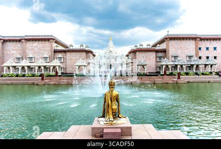 Robbinsville, New Jersey - US - 2 agosto 2025 Una tranquilla piscina con una statua dorata inginocchiata e fontane danzanti abbelliscono la facciata del BAPS Swaminarayan Akshardham Foto Stock