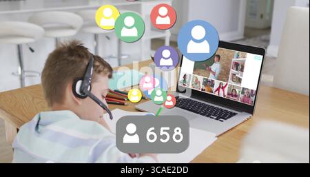 Durante il completamento dell'attività, lo studente indossa una cuffia a righe con un computer portatile e matite al tavolo della cucina Foto Stock