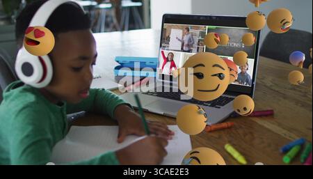 Scrivendo in età scolare indossando camicia verde e cuffie al tavolo con laptop, spazio per copiare Foto Stock