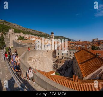 Dubrovnik, Croazia - 14 settembre 2023: I turisti esplorano le storiche mura della città, ammirando la vista sui tetti di tegole rosse. Foto Stock
