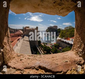 Dubrovnik, Croazia - 14 settembre 2023: I turisti esplorano le storiche mura della città, sbirciando attraverso un'apertura per vedere Fort Lovrijenac. Foto Stock