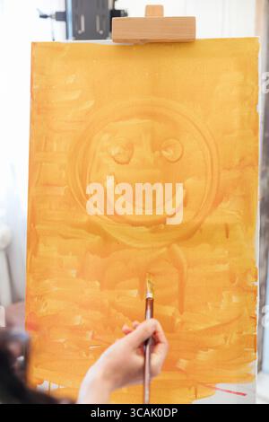 L'artista bruna dipinge un'immagine su cavalletto con dei pennelli Foto Stock