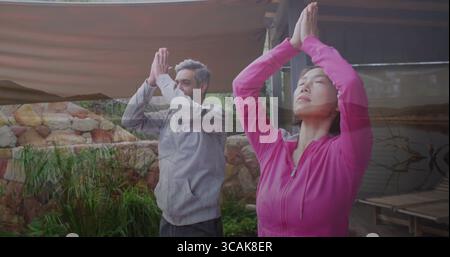 Pratica la coppia in abbigliamento sportivo mentre pratica yoga posa di preghiera sul ponte del giardino, con baldacchino e laghetto Foto Stock