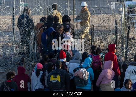 I civili, compresi i bambini, si riuniscono al confine di Ciudad Juarez sotto l'occhio di un soldato. Foto Stock