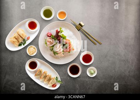 mix di piatti della cucina orientale con sashimi freschi e varie salse su sfondo di pietra. Vista superiore con spazio di copia. Foto Stock