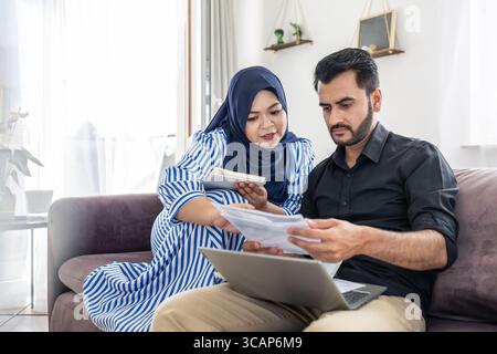 Coppia musulmana che usa il laptop insieme sul divano a casa Foto Stock