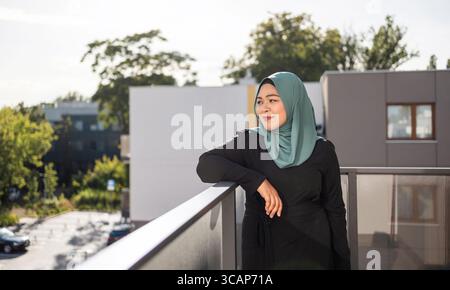 Giovane donna in hijab in piedi sul balcone Foto Stock