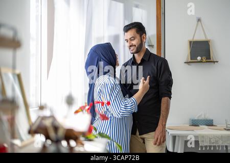 Una coppia musulmana amorevole in piedi nel soggiorno della loro casa Foto Stock