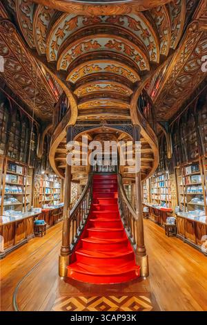 Scala all'interno della libreria Lello, famosa in tutto il mondo, a Porto, in Portogallo, che presenta un'intricata architettura in legno neogotico e dettagli del soffitto scolpiti Foto Stock