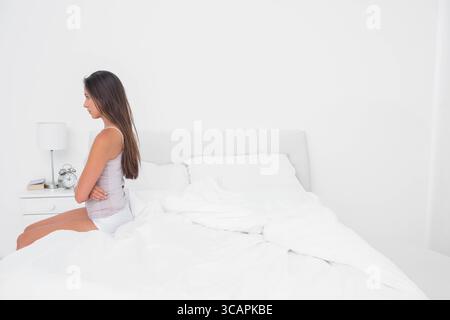 Letto bianco seduto su testiera coordinata nella camera da letto monocromatica, con biancheria da letto imbottita Foto Stock
