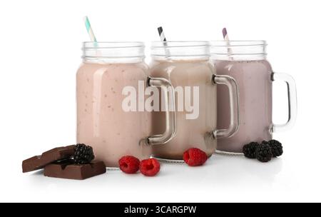 Diversi frullati gustosi nei vasetti mason e ingredienti isolati sul bianco Foto Stock