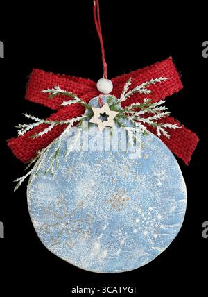 Palla per decorazione dell'albero di Natale fatta in casa in legno, intonaco e arco. Isolato sul nero Foto Stock