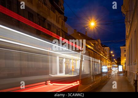 Foto notturna a lunga esposizione dei sentieri leggeri del tram che si snodano attraverso il centro storico di Timisoara, Romania. Foto scattata il 30 luglio 2025. Foto Stock