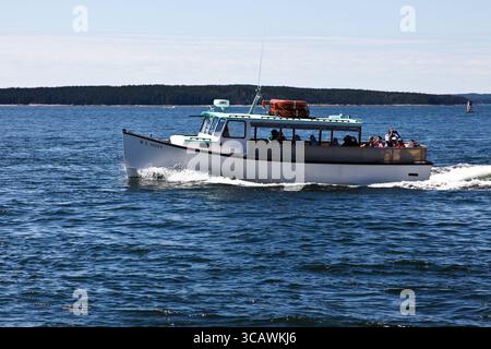 BASS Harbor, MAINE, Stati Uniti - 7 AGOSTO 2010: Una barca scivola attraverso le acque cristalline, trasportando un gruppo di passeggeri che stanno assaporando una splendida giornata. La lan Foto Stock