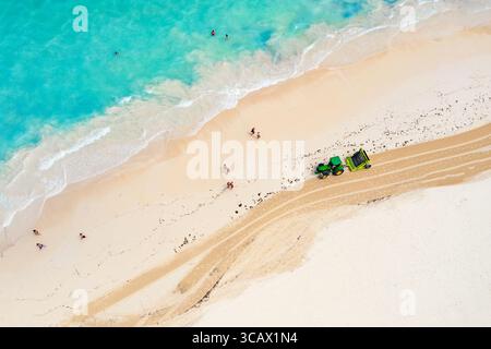 Vista aerea del trattore che pulisce la spiaggia dalle alghe. Spiaggia di Bavaro a Punta Cana, Repubblica Dominicana. Foto Stock