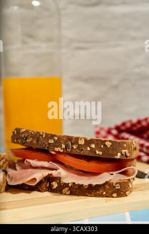 Due panini freschi serviti su una tavola di legno con un bicchiere e una bottiglia di succo di frutta Foto Stock