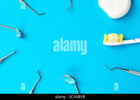 Igiene dentale e concetto di salute. Strumenti o strumenti dentali esploratori dentali, specchi dentali, filo interdentale e spazzolino da denti su sfondo azzurro Foto Stock