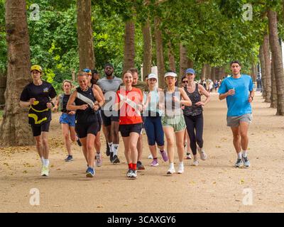 Un gruppo diversificato di persone che corrono insieme per il fitness e il tempo libero sui sentieri del St James's Park a Londra, Regno Unito. Foto Stock