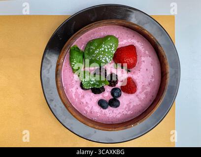 Sana ciotola per frullati di frutti di bosco con frutta fresca e foglie di basilico. Foto Stock
