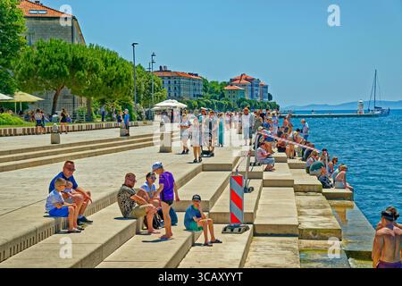 I visitatori ascoltano l'organo marino sul lungomare della città vecchia di Zara in Croazia. Foto Stock