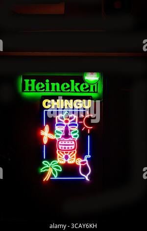 Colorato cartello al neon con marchio Heineken e disegni tropicali su sfondo scuro in un vivace ambiente urbano malese Foto Stock