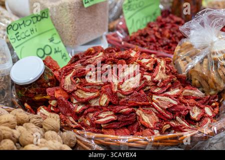 Un grande cesto di vimini pieno di pomodori secchi circondati da un vaso di vetro di pomodori conservati in olio in un mercato alimentare tradizionale Foto Stock