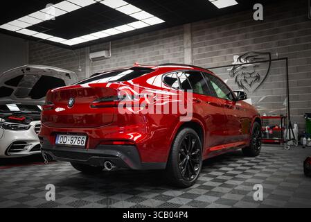 BMW X4 rossa e Mercedes G bianca in un moderno garage interno Foto Stock