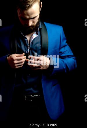 Un uomo con un vestito blu sta abbottonando la sua camicia. Foto Stock