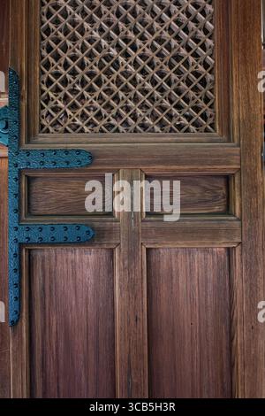 Una porta in legno splendidamente lavorata caratterizzata da un motivo a reticolo decorato e da una cerniera in ferro nero presso il tempio buddista Ryōan-ji, Kyoto, Giappone Foto Stock