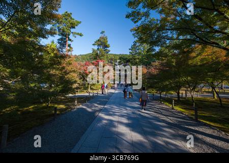 I visitatori passeggiano lungo un sentiero illuminato dal sole circondato da alberi in un tranquillo parco. Nanzenji Fukuchicho, Sakyo Ward, Kyoto, Kansai, Honshu, Giappone Foto Stock