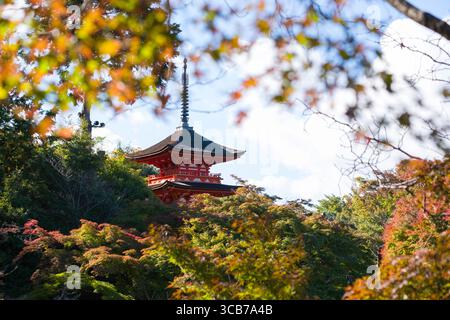La pagoda di Kiyomizu-dera Koyasunoto è circondata da foglie autunnali colorate, catturate in un ambiente tranquillo all'aperto contro un cielo luminoso e punteggiato di nuvole. Foto Stock