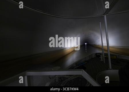 Il tunnel del canale del lago Biwa, illuminato in modo poco chiaro, mostra la sua profondità e l'atmosfera ombrosa, con una barca parzialmente visibile in primo piano, Kyoto, Giappone Foto Stock