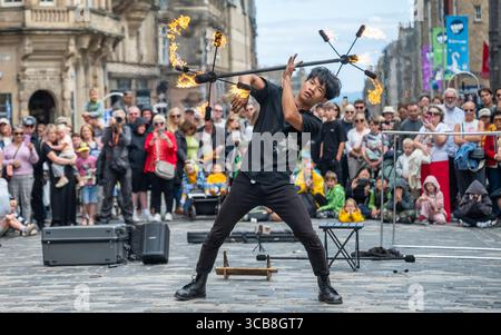 Edimburgo, Regno Unito. 7 agosto 2025. 7 agosto 2025 Edimburgo, Edinburgh Fringe Festival. L'Edinburgh Fringe è ora in pieno svolgimento e la folla si affolla al Royal Mile per sperimentare la varietà di talenti, immagini e suoni degli artisti di strada. Xiao Hei esegue la sua azione di fuoco davanti alla folla PIC Credit: phil wilkinson/Alamy Live News Foto Stock